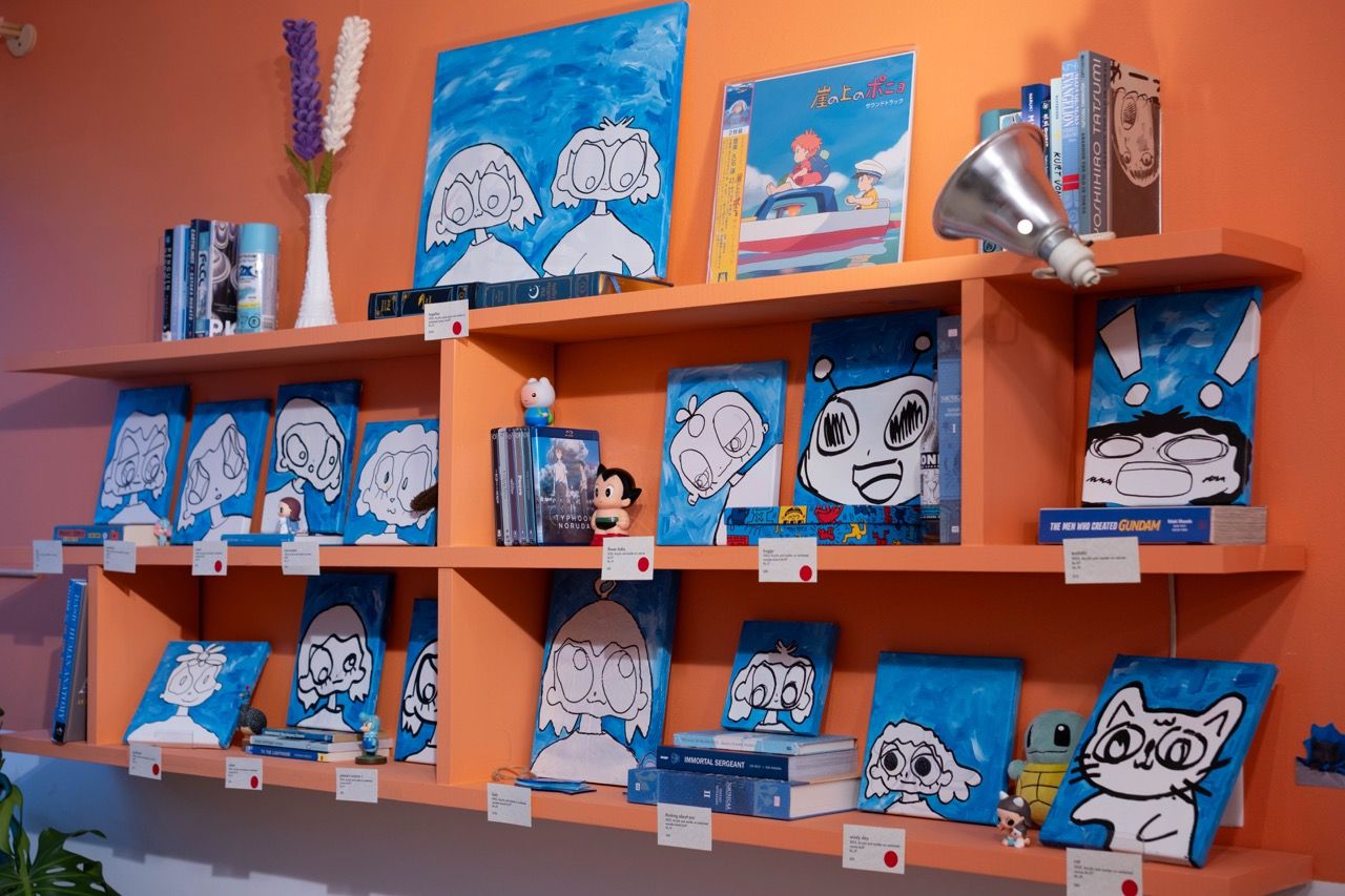 blue background paintings with different caricatures on each displayed on orange shelves