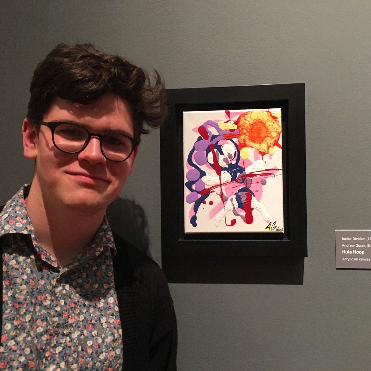 photograph of myself smiling in front of a framed painting in a gallery space