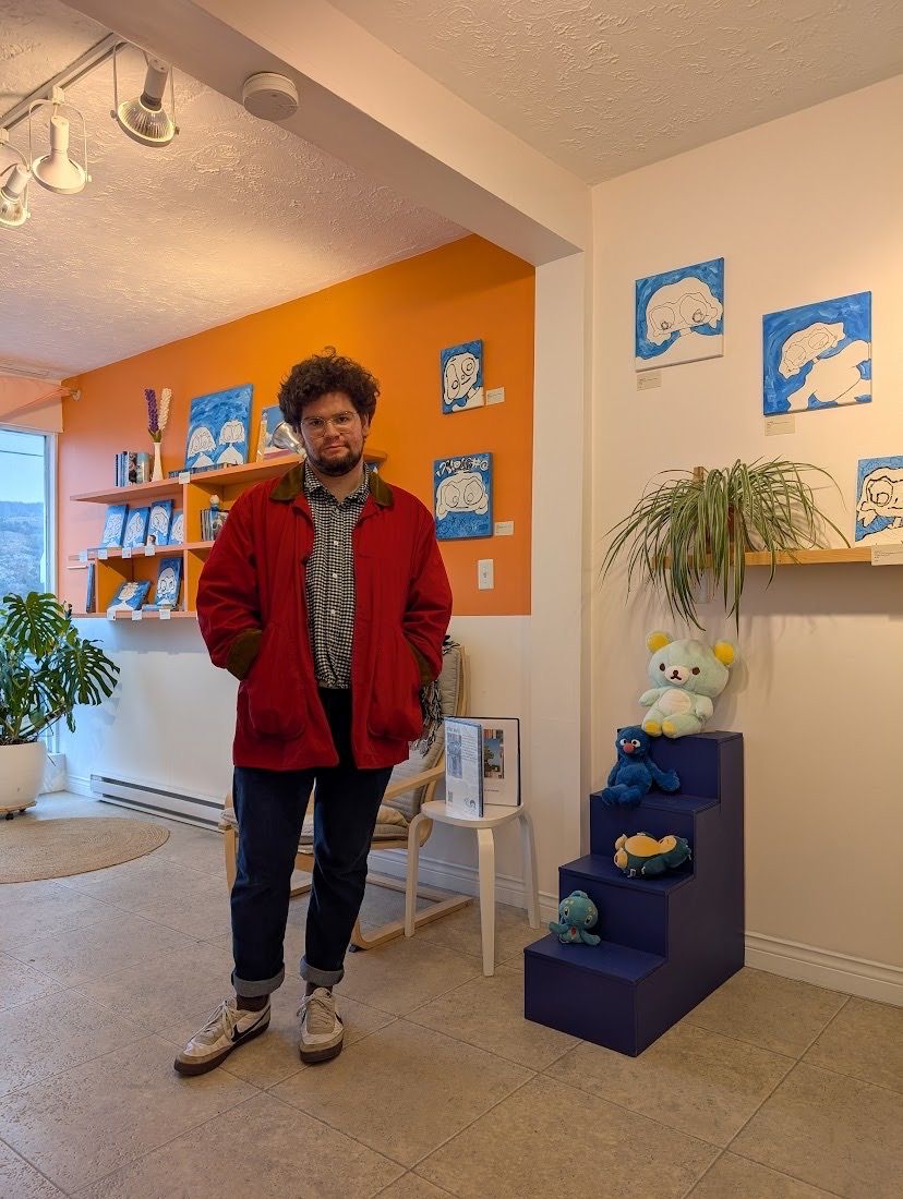 person in red coat smiling in front of various blue paintings on walls in background