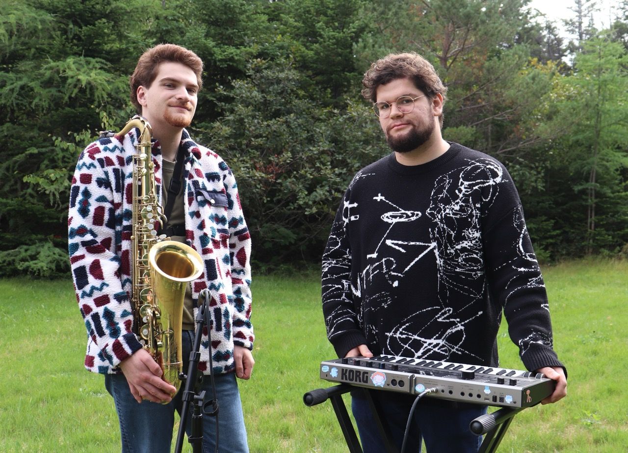 2 people posing outside, person on left holding saxophone and myself holding synthesizer